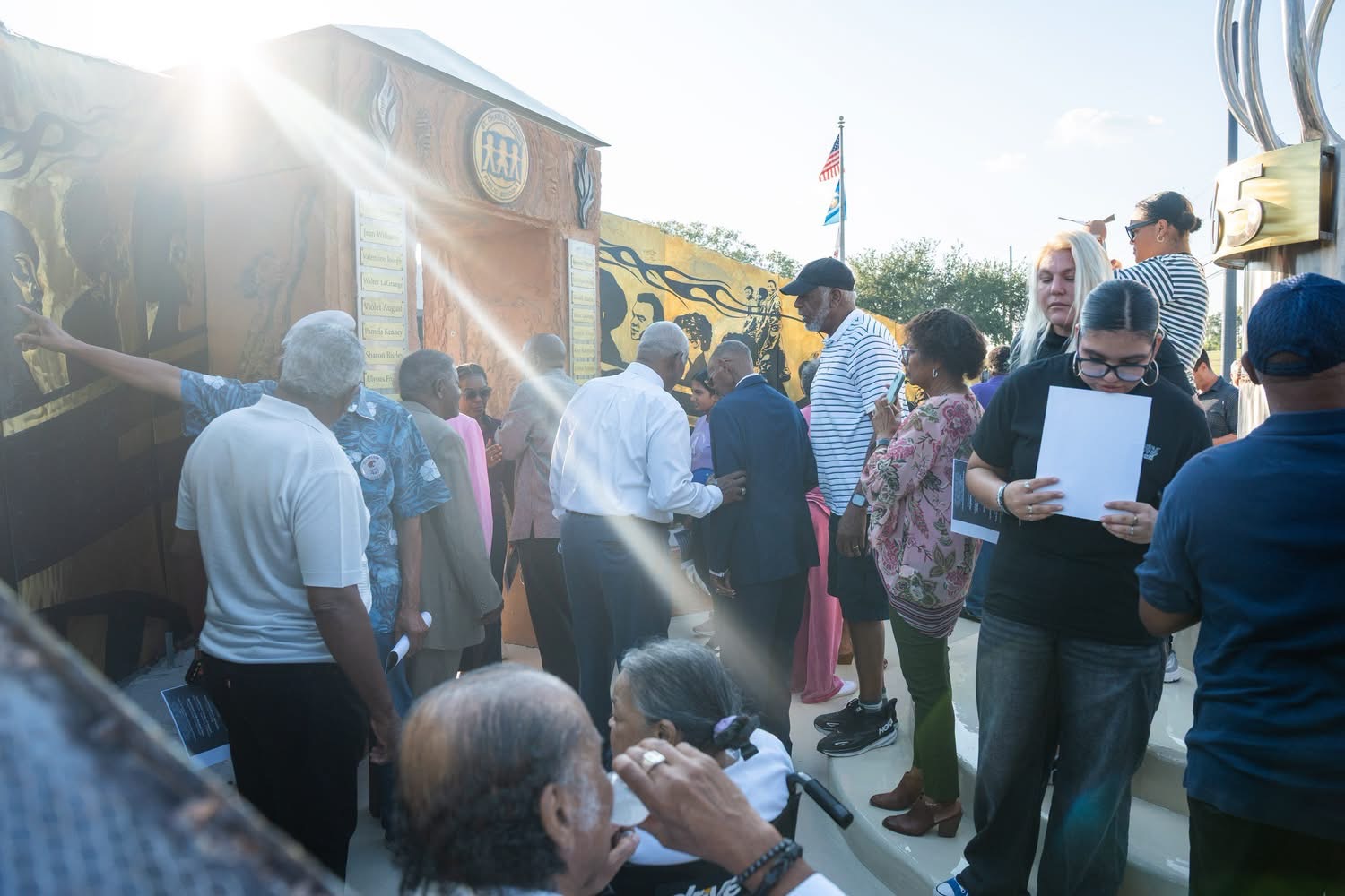 Sunlit crowd gathered at the memorial entrance