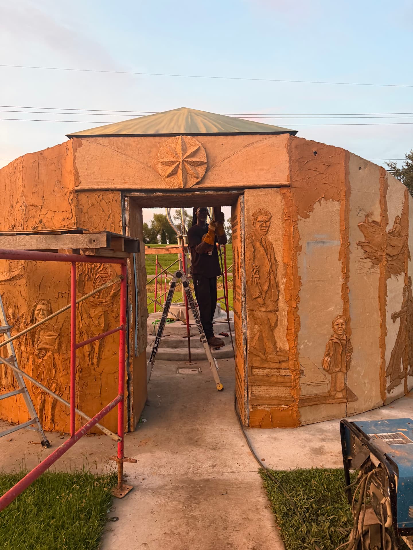 The 43 Trailblazers Memorial under construction, with sculpted clay reliefs and scaffolding around the structure