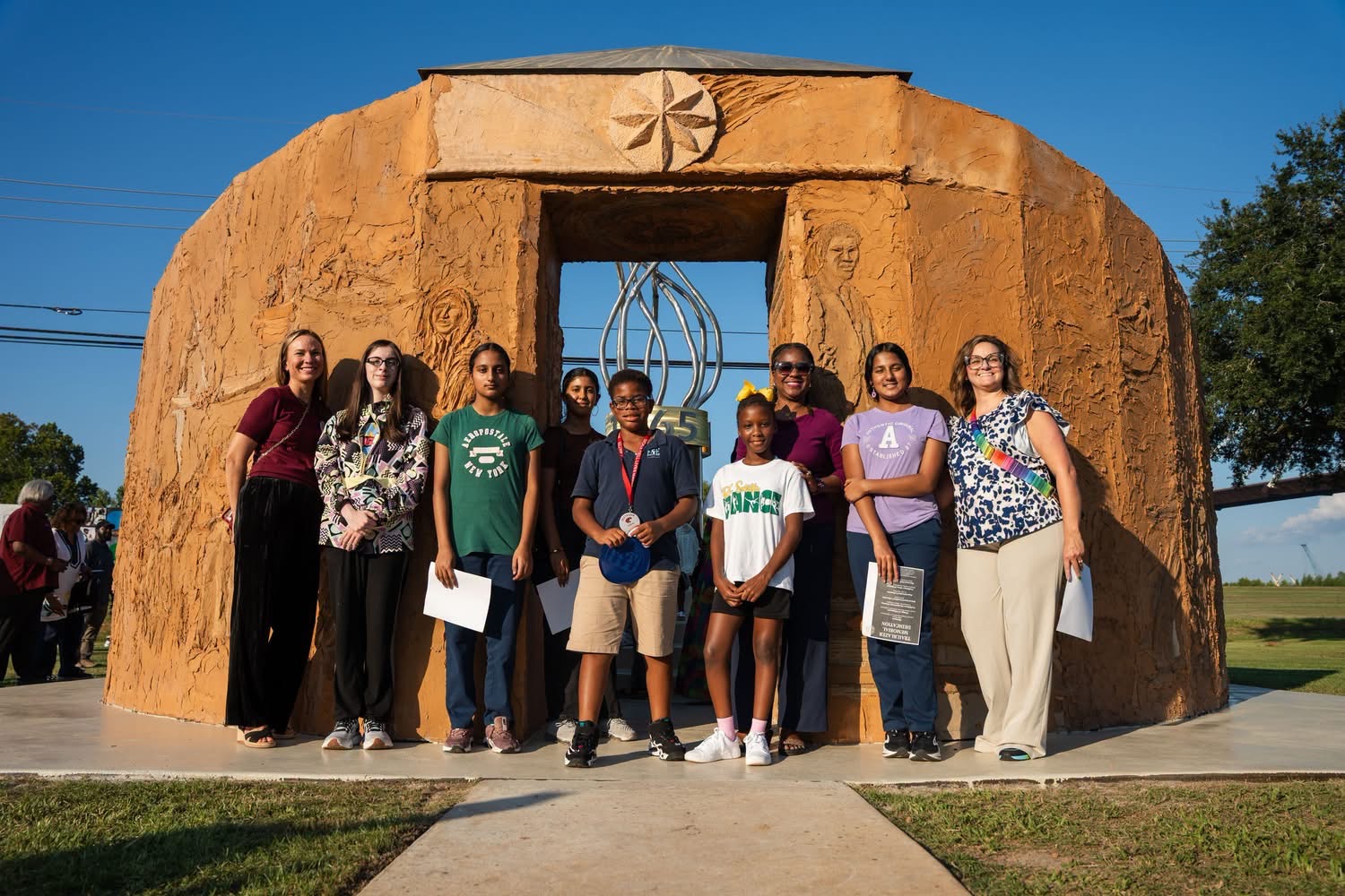 Students and teachers posing in front of the completed memorial arch