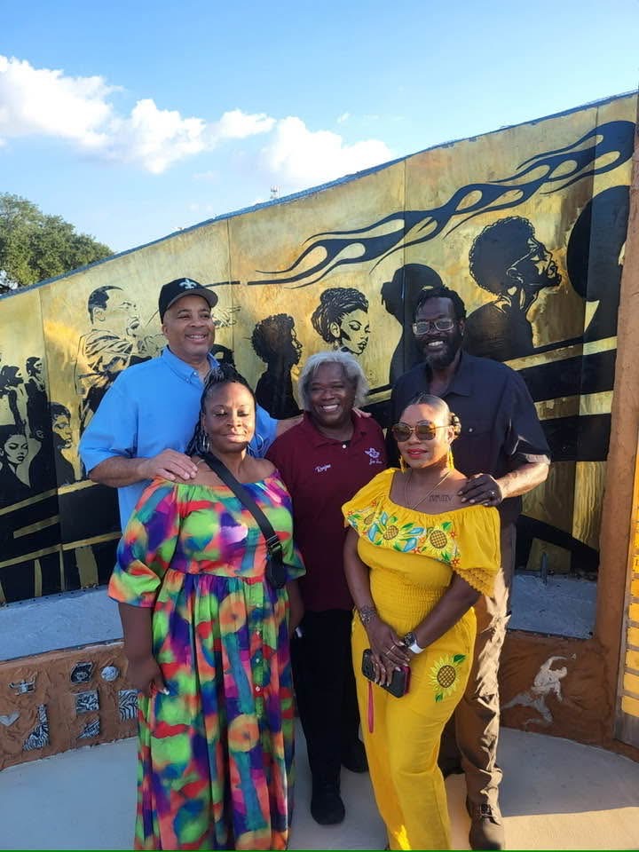 Family members posing together in front of the memorial mural